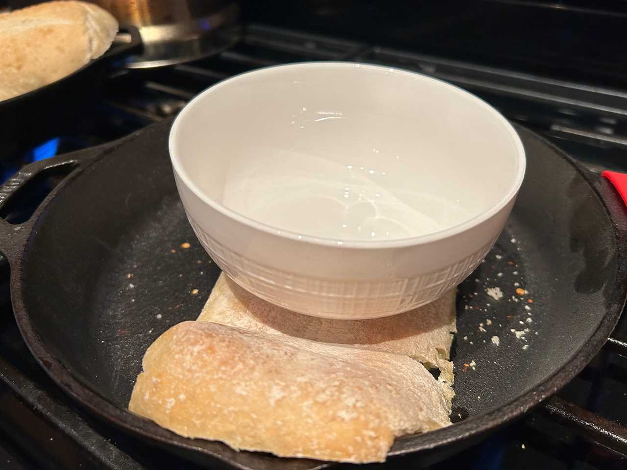 Ciabatta bread in a cast-iron skillet with a white bowl sitting on top.