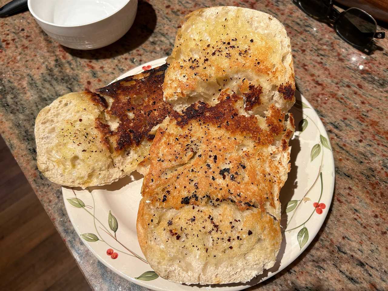 Two pieces of ciabatta bread that are burned in spots on a plate.