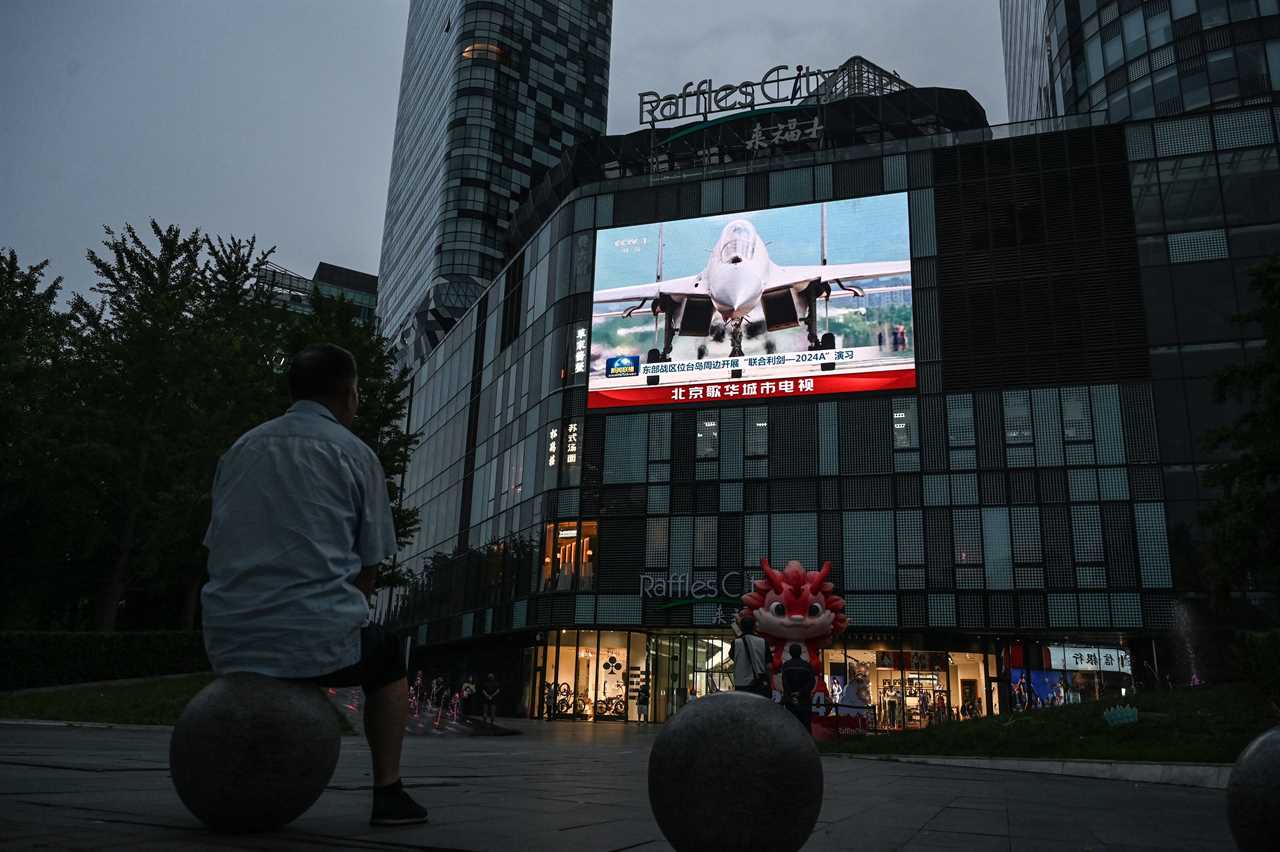 An outdoor screen shows a news coverage of China's military drills around Taiwan, in Beijing on May 23, 2024.