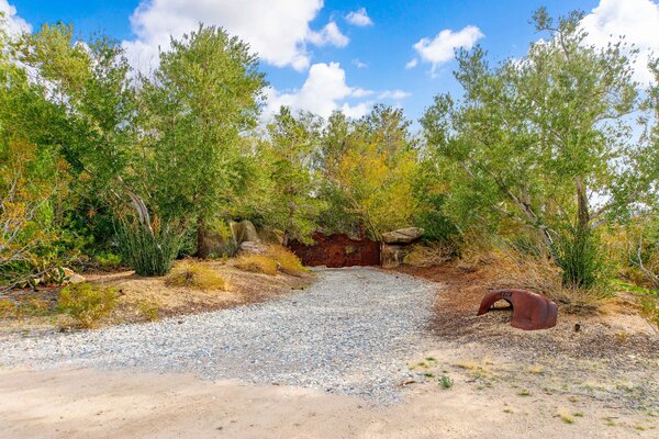 Soaring trees and rocks surround the property, which is accessed via a gated entrance.