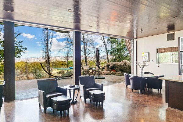 Expansive floor-to-ceiling glass doors line the rear of the home, connecting the main living areas with the backyard patio overlooking the nearby Joshua Tree National Park.