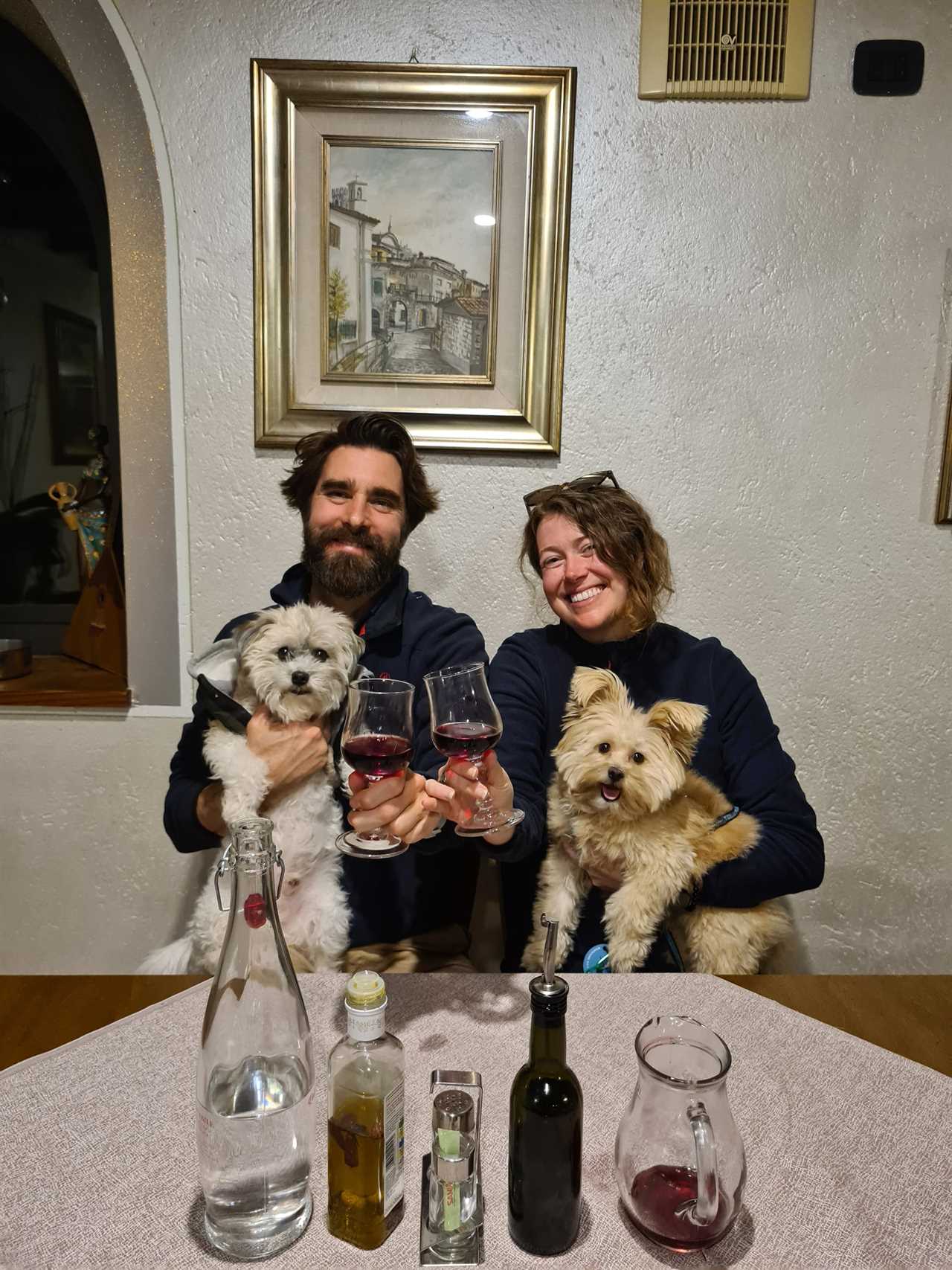 Kristina Knighten and Paul Cordier holding two small dogs and glasses of wine.