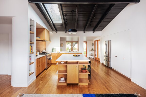 Engelsman gave the kitchen an L-shaped layout with a large island workspace at the center, and pushed the tall storage into the garage, to create a wide circulation space to access the dining room and backyard.