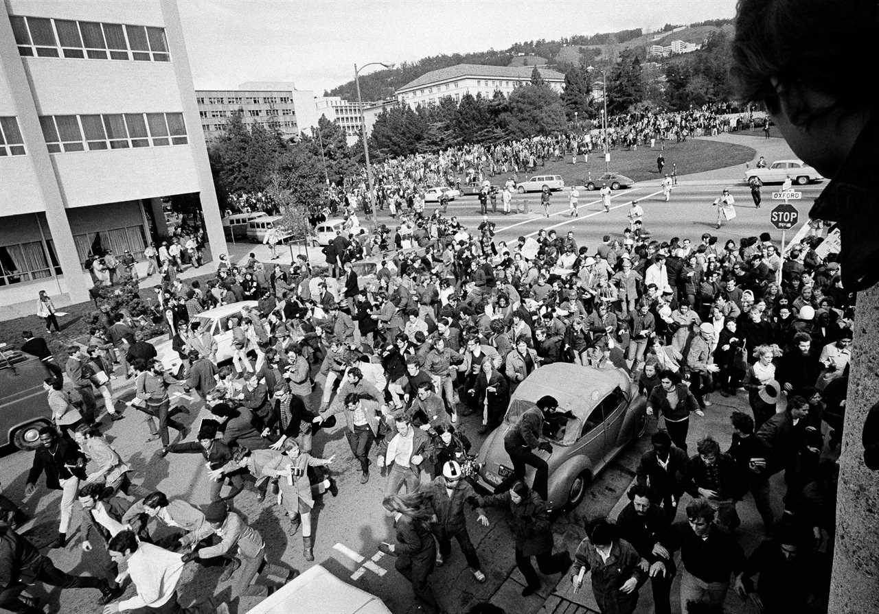 A crowd of students running into UC Berkeley as police move in.