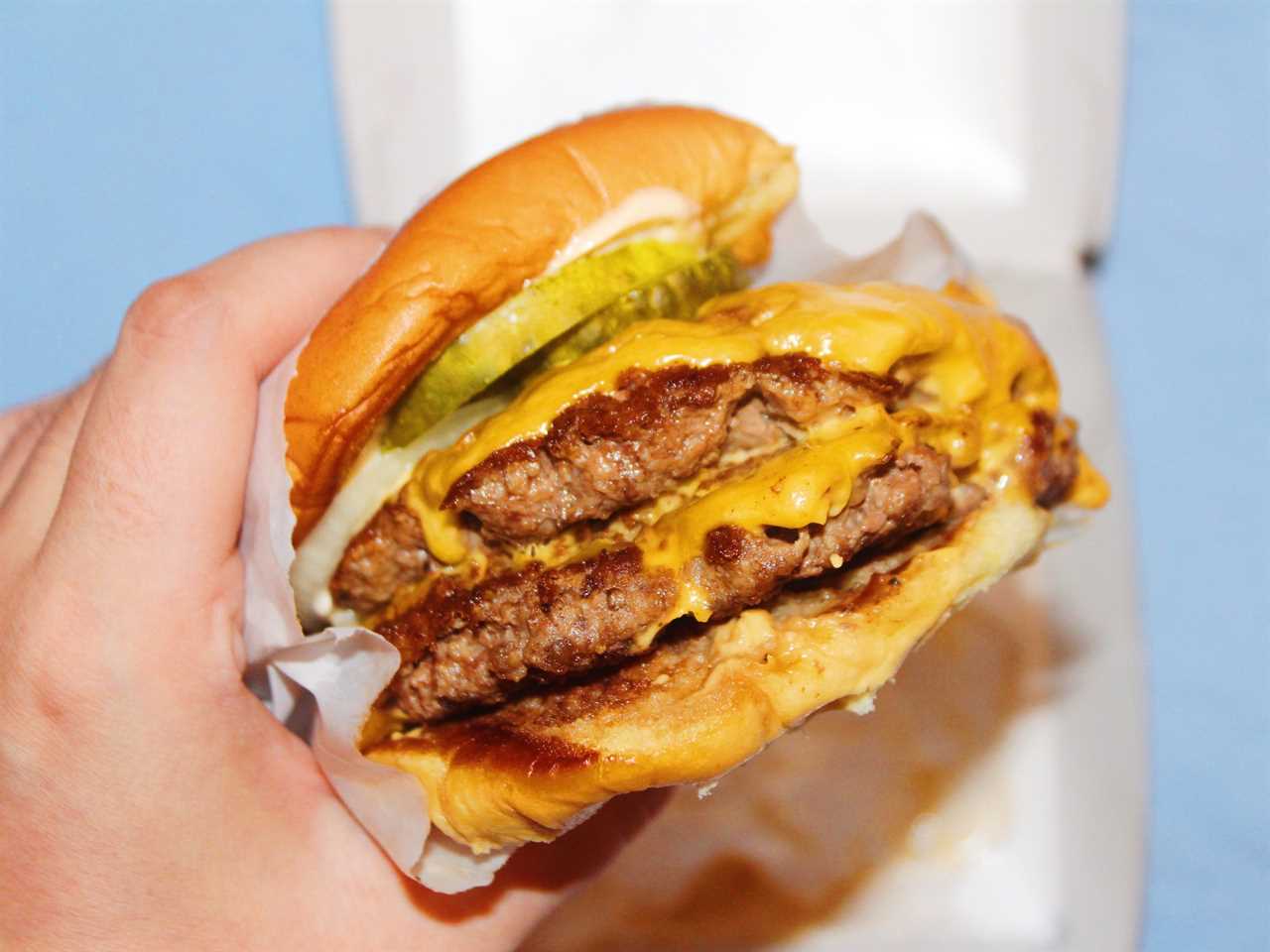 shake shack double cheeseburger in paper wrapping on blue background