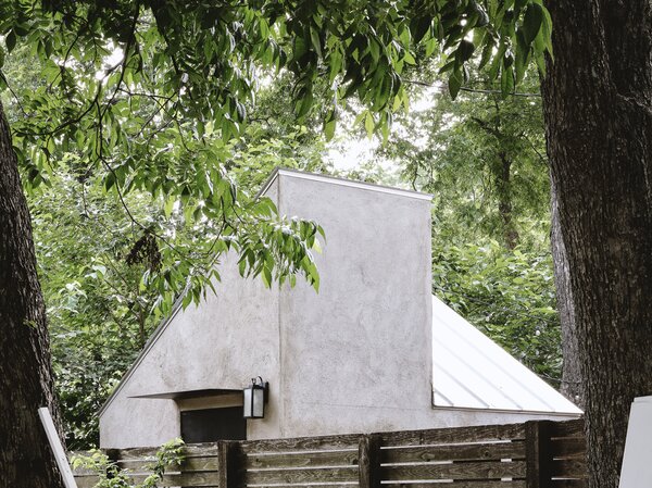 As a complement to the main home’s navy stucco facade and flat roof, the office exterior siding is a sandy gray stucco topped with a metal split shed roof.