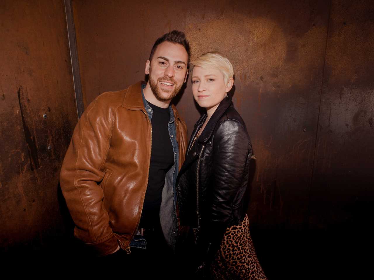 A couple standing in front of a wall.