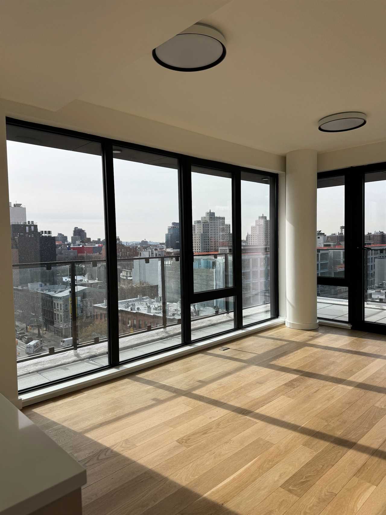 An empty apartment surrounded by floor-to-ceiling windows.