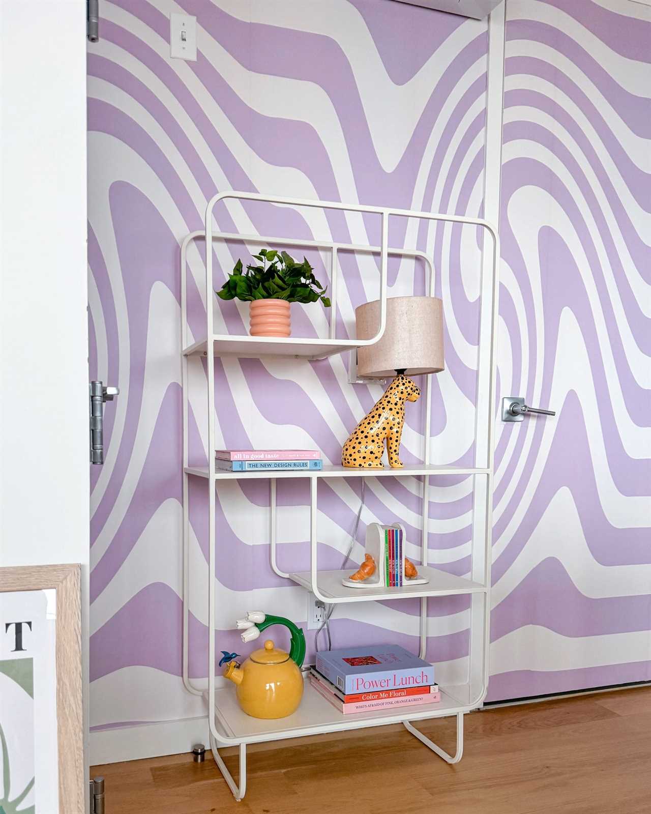 A purple and white wall with a bookshelf in front of it.