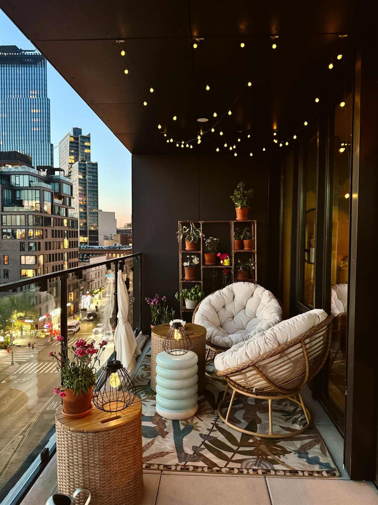 A patio with twinkly lights, a colorful rug, round chairs, and plants.