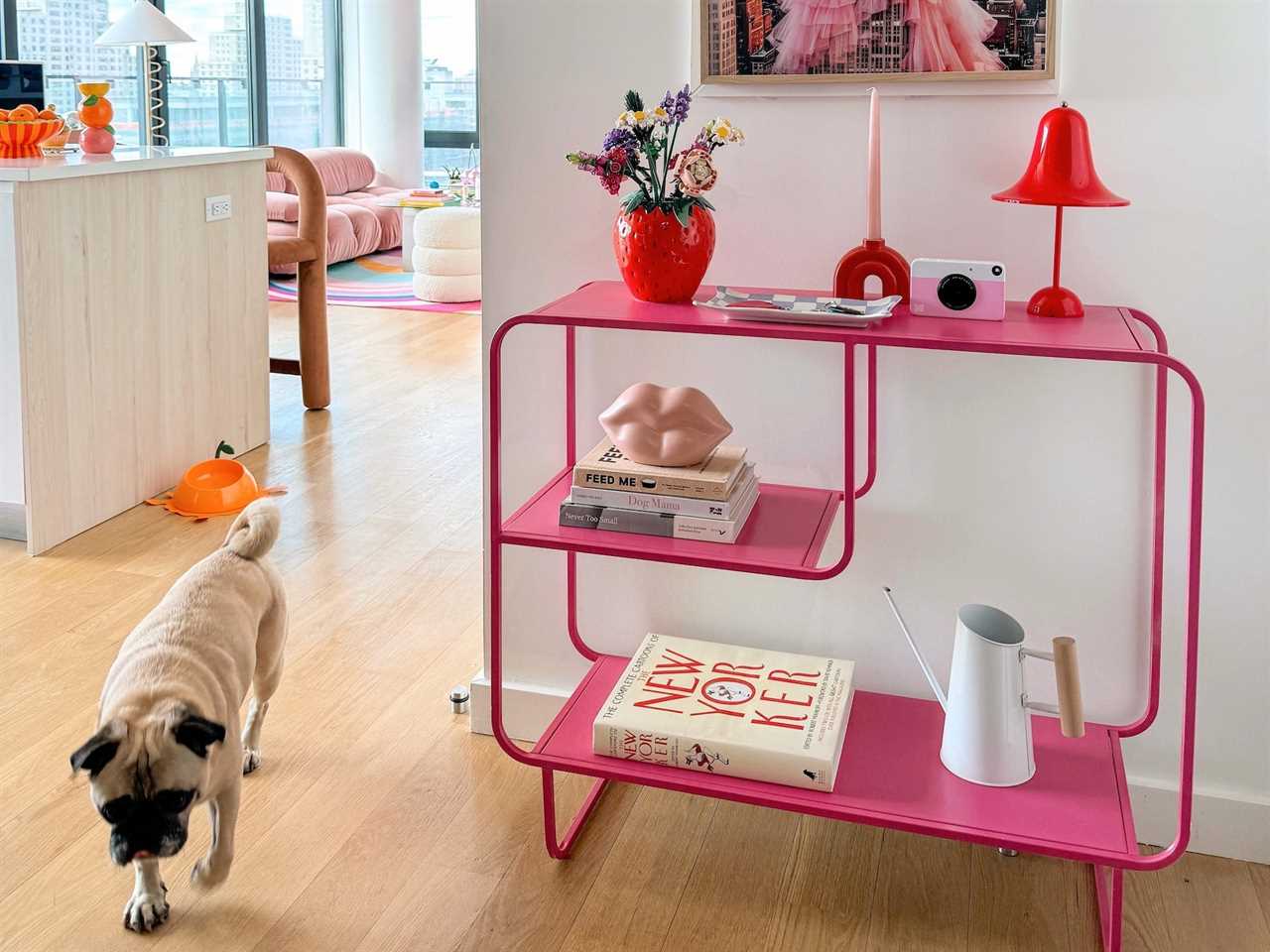 A pink shelf sits on a white wall with colorful knickknacks on it.