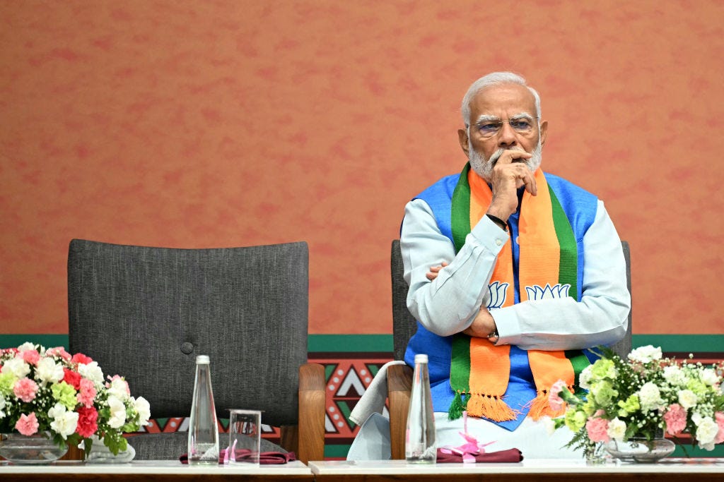 Narendra Modi sitting at a table with flowers on it.