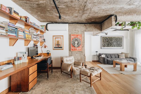 <span style="font-family: Theinhardt, -apple-system, BlinkMacSystemFont, "Segoe UI", Roboto, Oxygen-Sans, Ubuntu, Cantarell, "Helvetica Neue", sans-serif;">The architects created an office for two in the open living area by arranging a Freijó wood desk along the wall. Shelving above the desk holds Carolina and Marcus's book collection, and the armchair and ottoman, designed by Sergio Rodrigues, were acquired at auction; the poster is by Shepard Fairey. The sitting area is outfitted with a family heirloom coffee table, a sofa by Cini Boeri, and a Jackson Pollock print.</span>