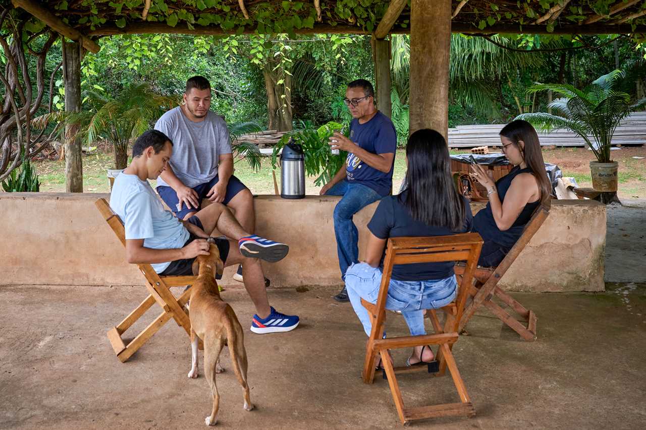 five people with a dog, seated outdoors under a pergola