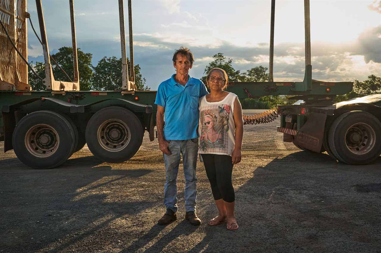 Antônio Gilberto Lima and Ana Cláudia Gregório Braguim standing in front of semi trucks