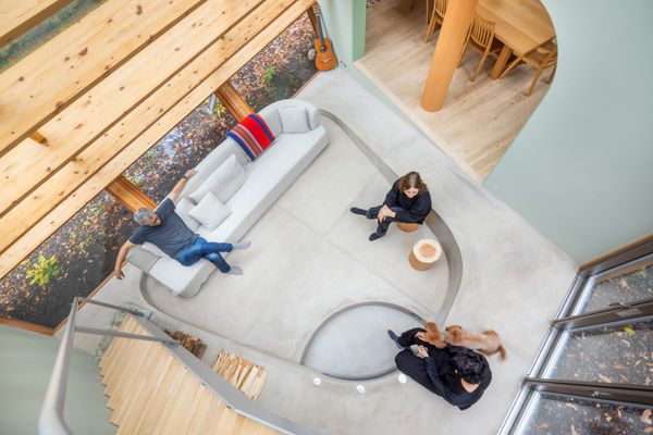 A home in Karuizawa, Japan, designed by Rei Mitsui of Tokyo-based Rei Mitsui, embraces the land in a gently arced design. In the sunken living room, homeowner Rob Tull relaxes on a lin-en couch designed by Mitsui and made by Tetsuhiro Otsuka of Hiro & Associates. The recessed area’s rounded edges, echoed in the arched entryway to the kitchen and the curved ends of the staircase’s handrail, soften the home’s angularity.