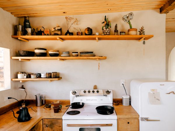 Aaron guesses the appliances, sink, and window in the kitchen are original. Aaron and Prescott worked together to update the counters and fashion new cabinetry from scraps lying around the property. The ceramic bowls are by Andrea Zittel.