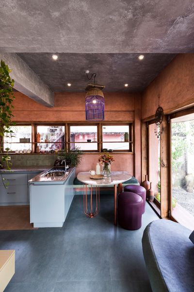 The dining table was custom-made from scrap, with salvaged stone slabs for the surface and bent TMT bars forming the legs. NO Architects drew up the design and it was crafted by a local artisan. The sofa and built-in bench were also crafted from leftover materials, resulting in the playfully mismatched upholstery.