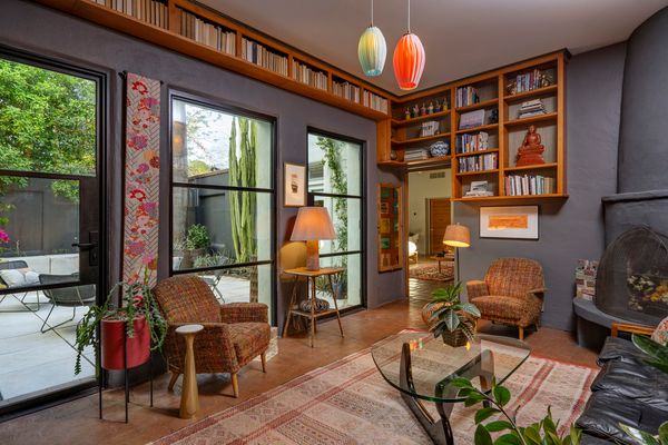 A sun-filled library with built-in bookshelves, steel-framed glass doors and windows, and a softly curved beehive fireplace invites reflection and relaxation.