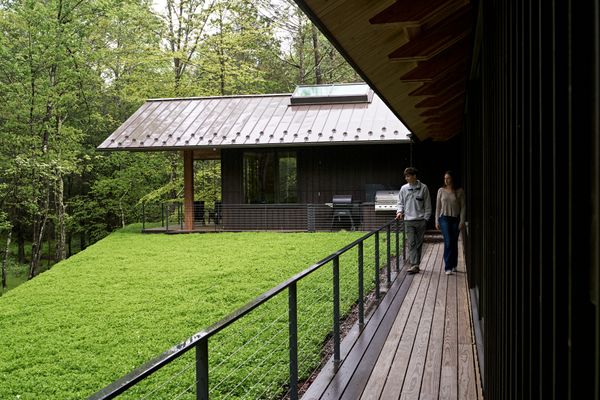 The cedar-clad pavilion hovers above a bluestone base. A covered terrace with a fireplace allows the family to enjoy the outdoors even in colder months.