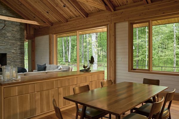 The open-plan living and dining area frames views of the surrounding woodland through expansive Marvin Ultimate windows with a Douglas fir interior.