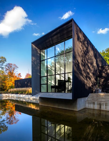 A two-story commercial glass and aluminum window is reflected in the property’s pond. The ends of the home taper to form a 