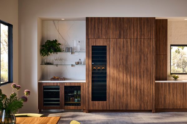 The Refrigerator and Freezer Columns seamlessly integrate into the walnut joinery, while the Beverage Refrigerator and Wine Cellar feature elegant glass fronts that showcase their contents as part of the design. 