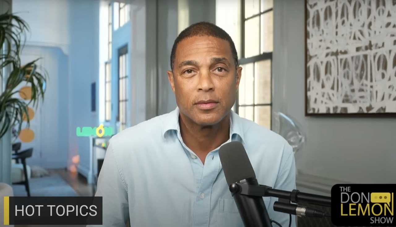 Don Lemon discussing hot topics on his show, featuring a modern studio backdrop with plants and a microphone.