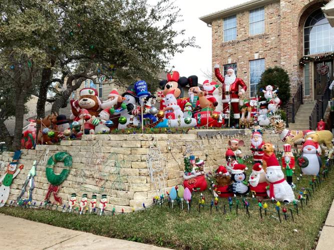 Front yard full of Christmas decor, inflatables, and statues.