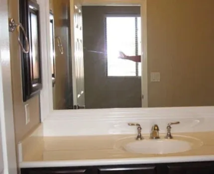 Bathroom shot from outside the door with a hand appearing in the mirror with the flash on.