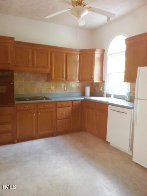 Outdated kitchen with wooden cabinets and harsh lighting