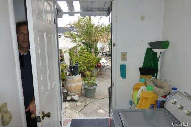 Mudroom with exterior door open to outside with a man hiding behind the door.