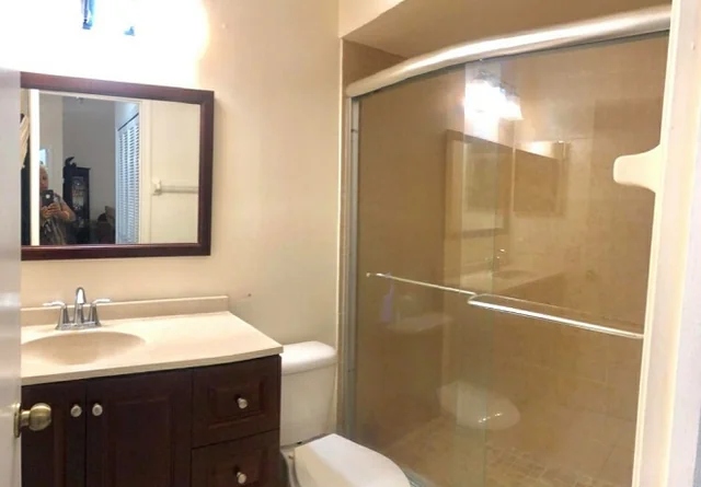 Small bathroom with the photographer showing in the mirror.