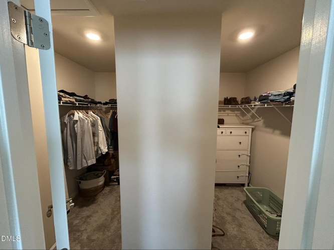 Ssplit closet with clothes on each side and a wall in the middle