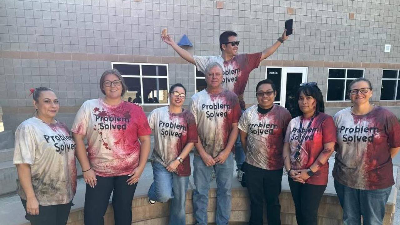 Group of eight individuals wearing matching "Problem Solved" t-shirts with a red and white design, posing outdoors in front of a building.