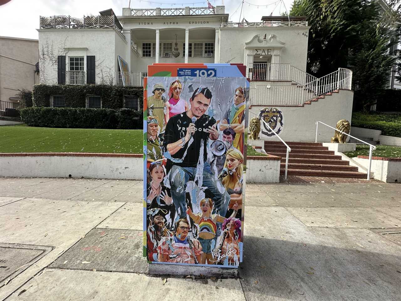 Colorful street art mural featuring various characters on a utility box in front of a historic building, showcasing vibrant urban culture.