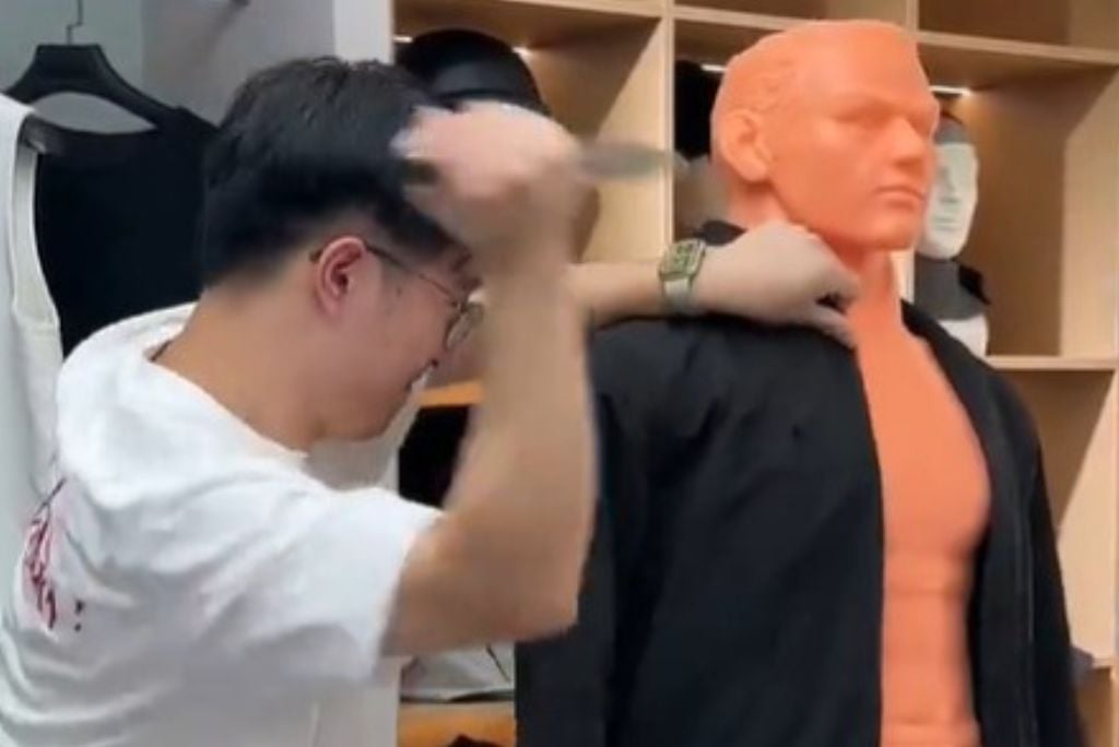 Person practicing self-defense techniques on a training dummy in a clothing store setting.