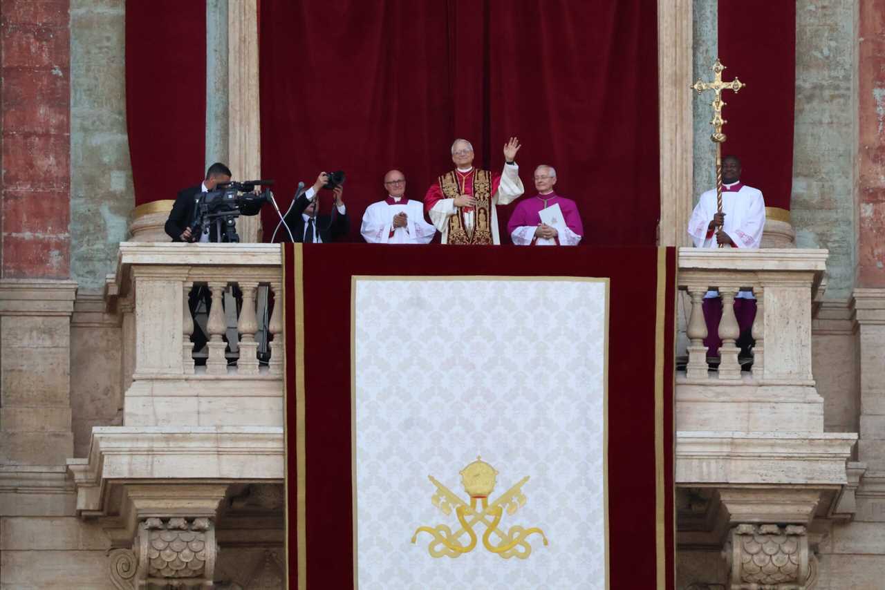 Pope and clergy members appear on the balcony of St. Peter's Basilica, greeting the crowd during a ceremonial event with a large decorative banner.