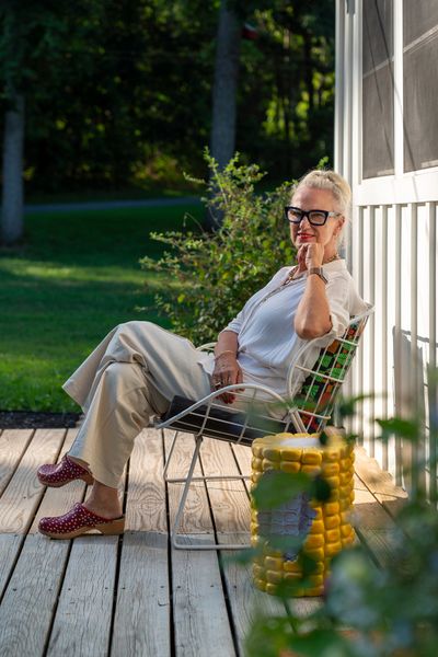 Designer and homeowner Ghislaine Viñas sits in on a vintage metal bench on the front porch.