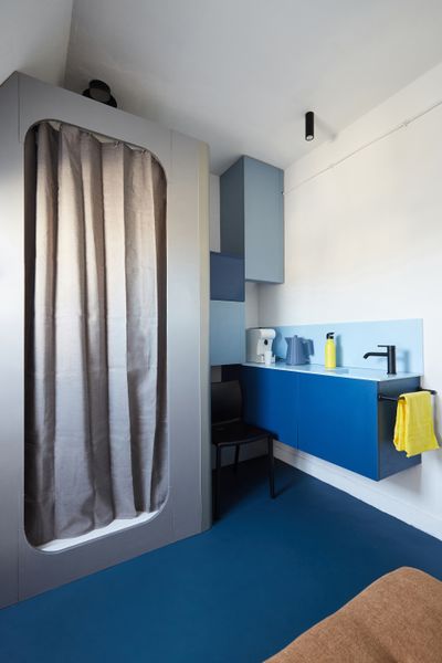 Shades of blue in the kitchen and flooring add to the compact apartment's nautical inspiration.