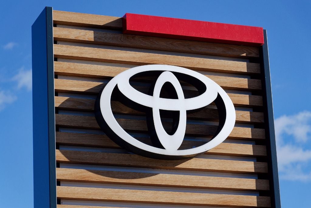 Toyota logo displayed on a modern wooden sign against a clear blue sky, representing the automotive brand's identity and commitment to quality.