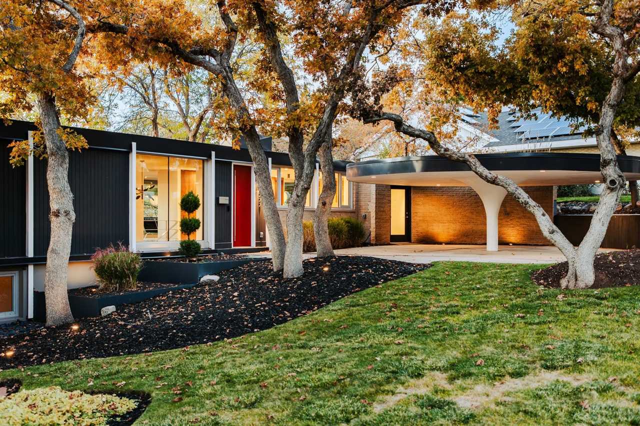 Designed by Swiss architect Eduard Dreier, the updated 1956 home has an original tulip-style carport, floor-to-ceiling windows, and a bright-red front door.