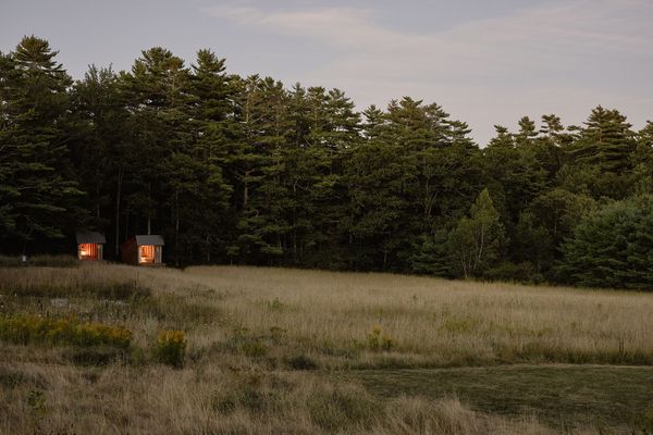 The tiny, open sleeping shelters abut a stand of woods. Their open fronts frame views of the Wanderwood farm.