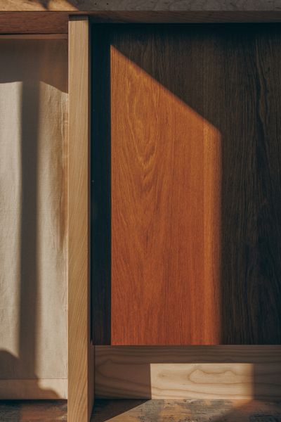 The cabinets, seen here, are made of brown oak, oak, and ash, and their clean lines and varied grain patterns work harmoniously with the floor, in all its rugged glory.