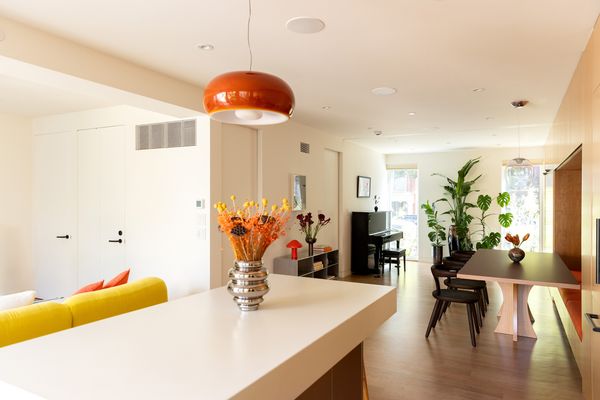 A glossy orange pendant adds a bold, warm pop against neutral tones, perfectly complementing the kitchen’s poured concrete countertop.