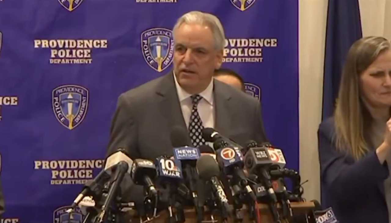 Providence Police Department press conference featuring officials discussing a recent incident, with multiple microphones in front and a blue backdrop.