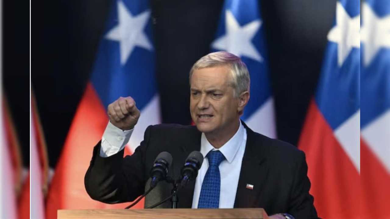 Politician delivering a speech with Chilean flags in the background, expressing determination and leadership during a public address.