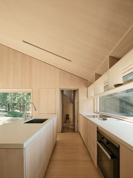 Douglas-fir open shelving and cabinetry were designed to match the wood in the rest of the home. The refrigerator is hiding beside the hallway entrance.