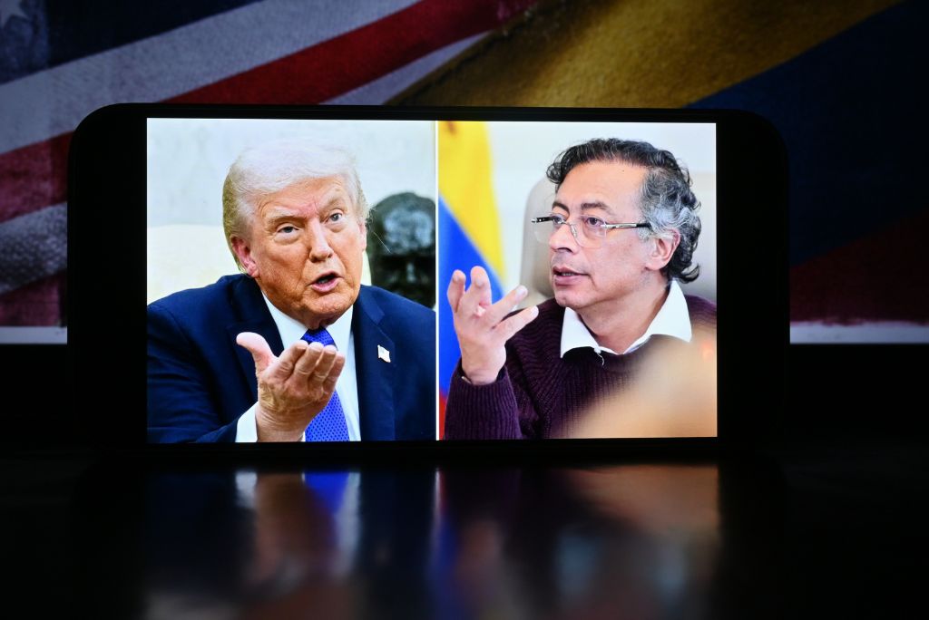 Image of Donald Trump and Gustavo Petro engaged in a discussion, displayed on a smartphone against a backdrop of flags, highlighting international political dialogue.