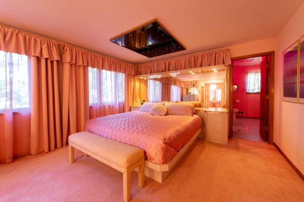 The bedrooms all have names; this one, called Star-Crossed, required some careful positioning to avoid putting the bed against the windows. They ended up covering a door that led to a small storage attic, using curtains to completely hide it from view. Inspired by a room at Cove Haven Resort, they were determined to install a star ceiling, which are a regular feature at kitschy hotels, and used Flex Ceilings to get it done.